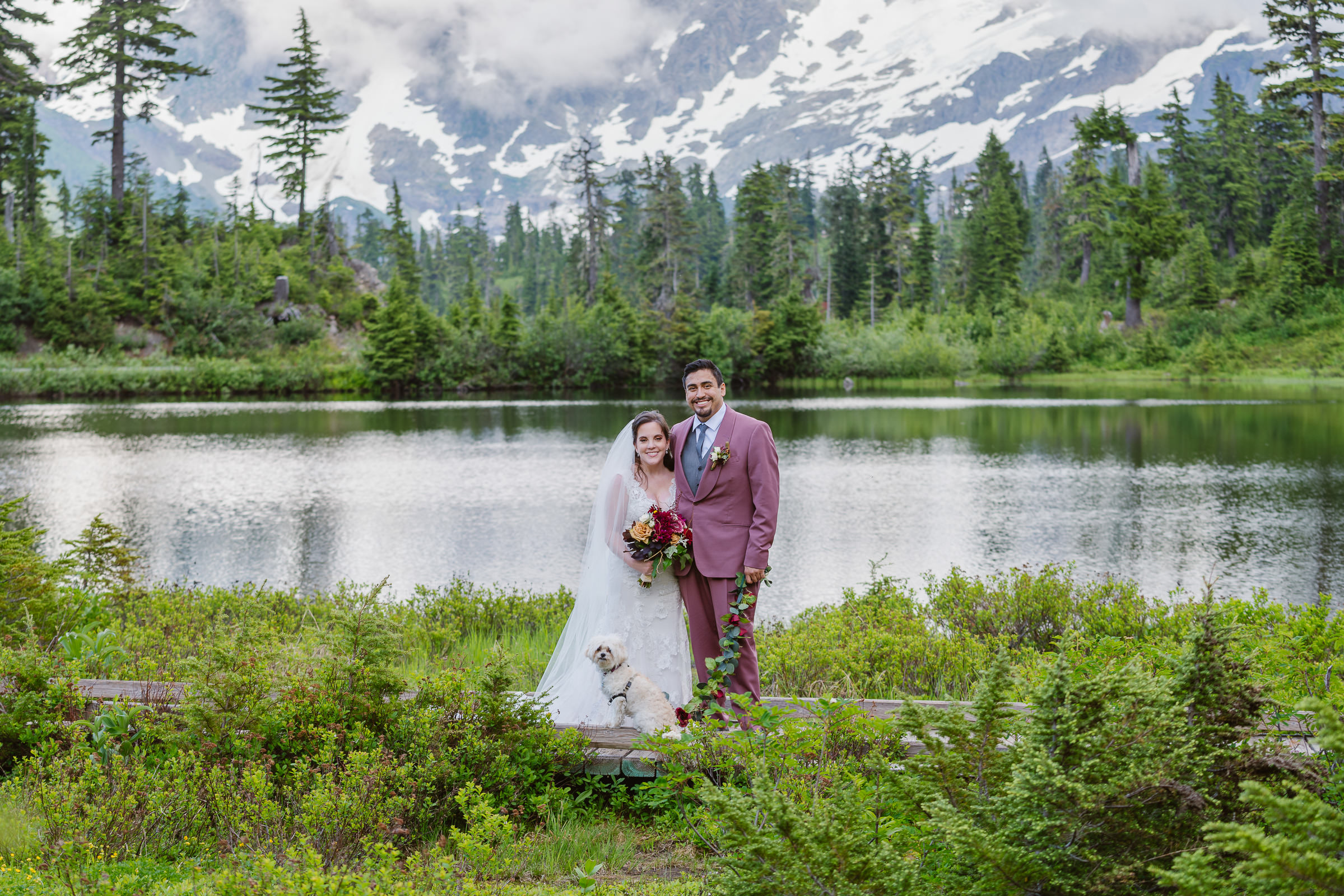 couple standing on trail with picture lake and mount shuksan behind them