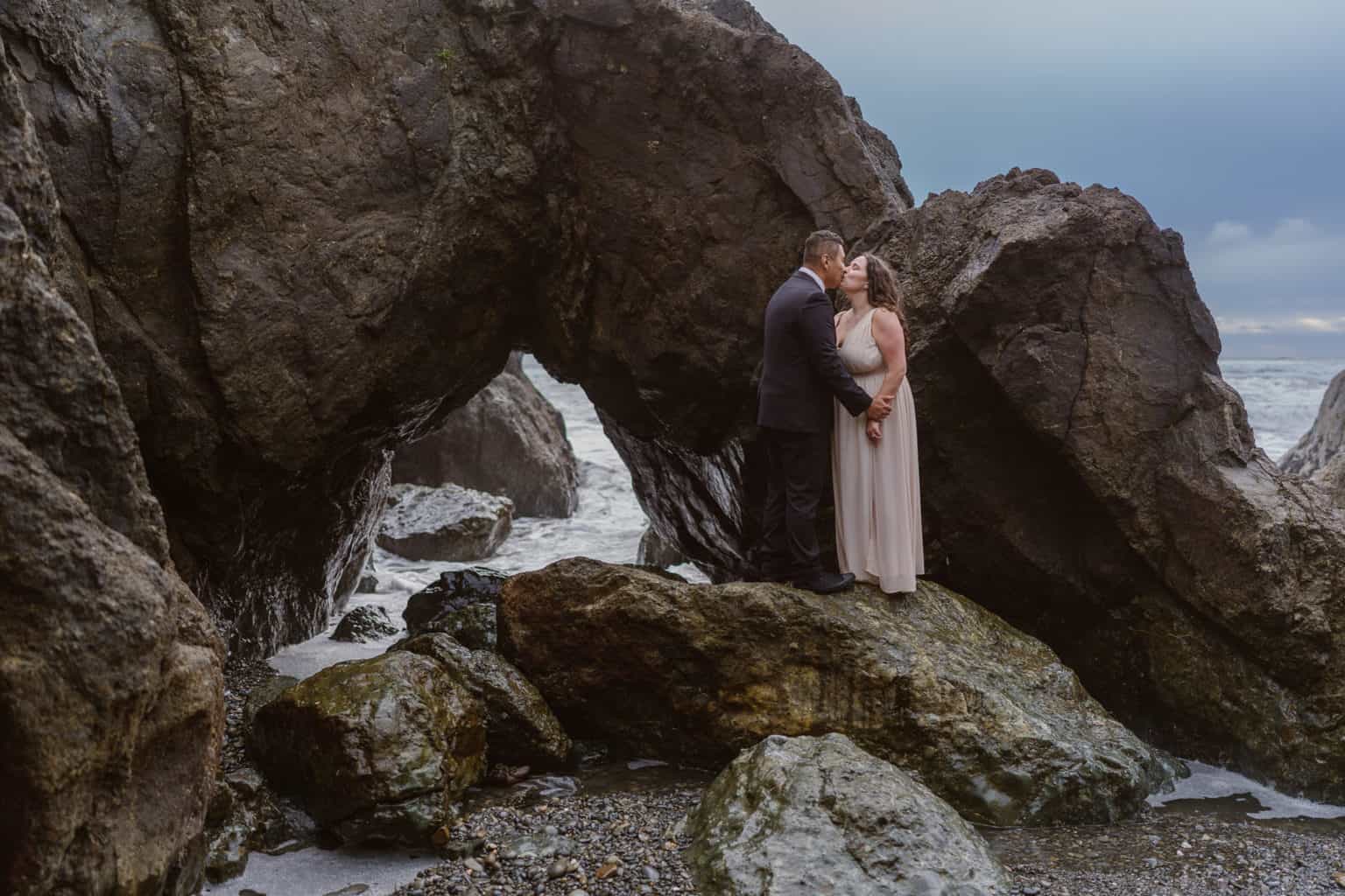 Couple kisses on rocks on Ruby Beach at sunset of their elopement day