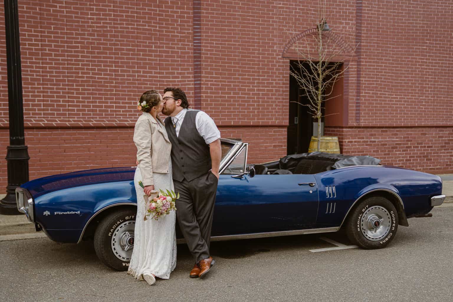 Couple enjoys a kiss next to their classic car on their adventure elopement in Snoqualmie
